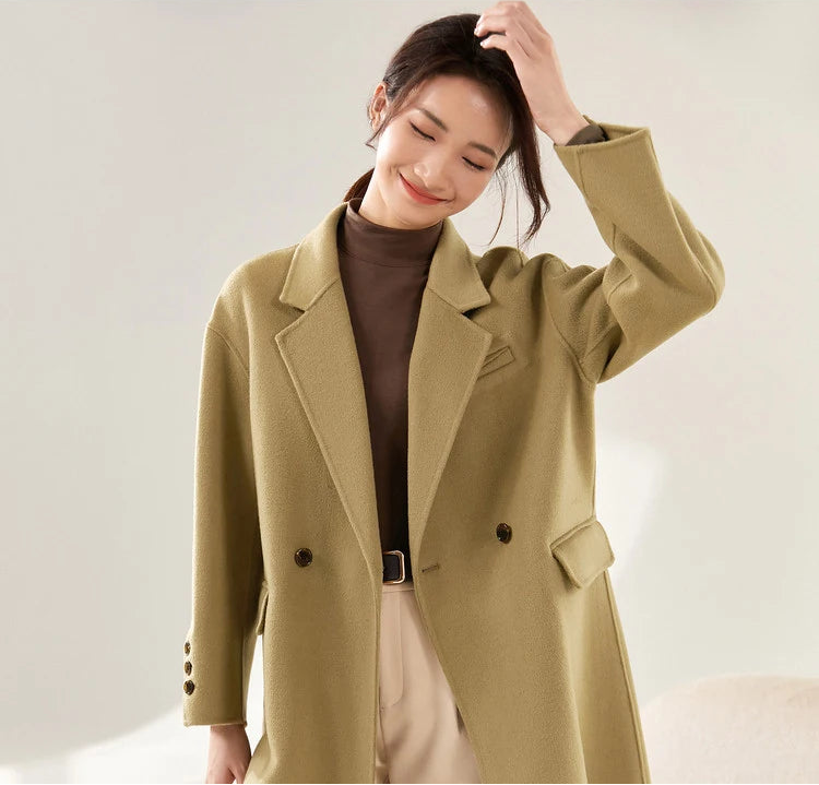 From Borcelleclothes: A model in the olive-toned Her Melody coat adjusting her hair, showcasing the relaxed elegance and weightless feel of the handmade double-faced design.