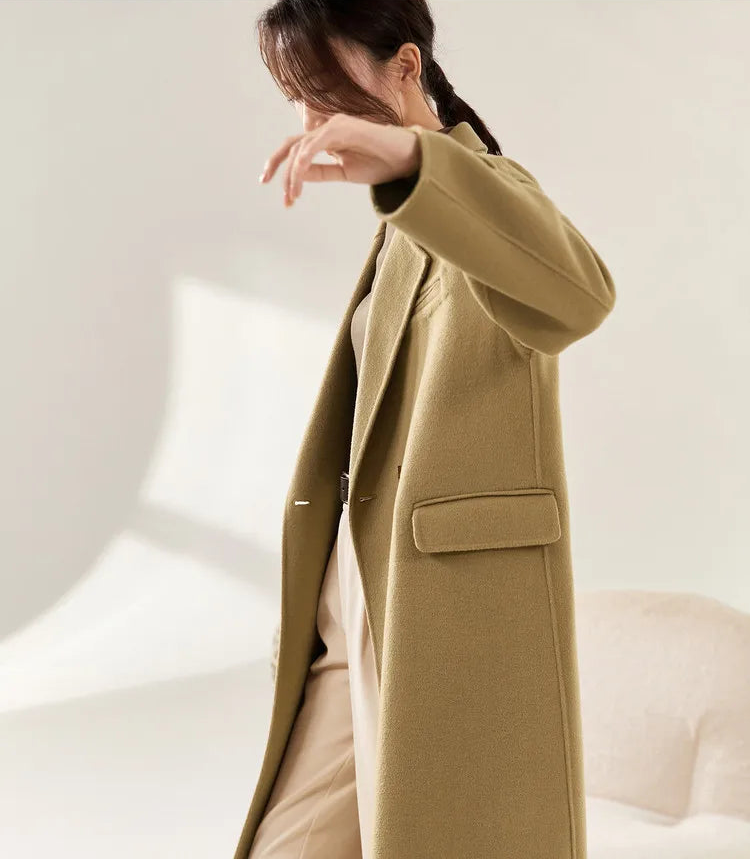 From Borcelleclothes: Side view of a model in the Do-Re-Mi coat with a raised arm, emphasizing the stepped three-button cuff placket and the natural flow of the wool.