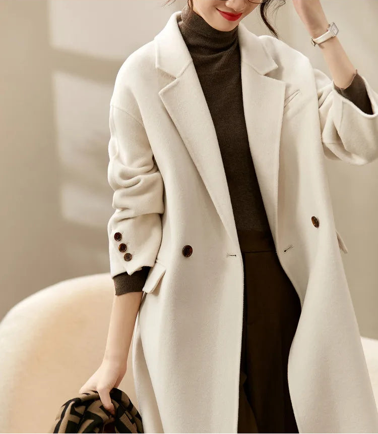 From Borcelleclothes: A model in the unfastened ivory wool coat with a raised arm, demonstrating the weightless movement and grace of the 100% wool material.