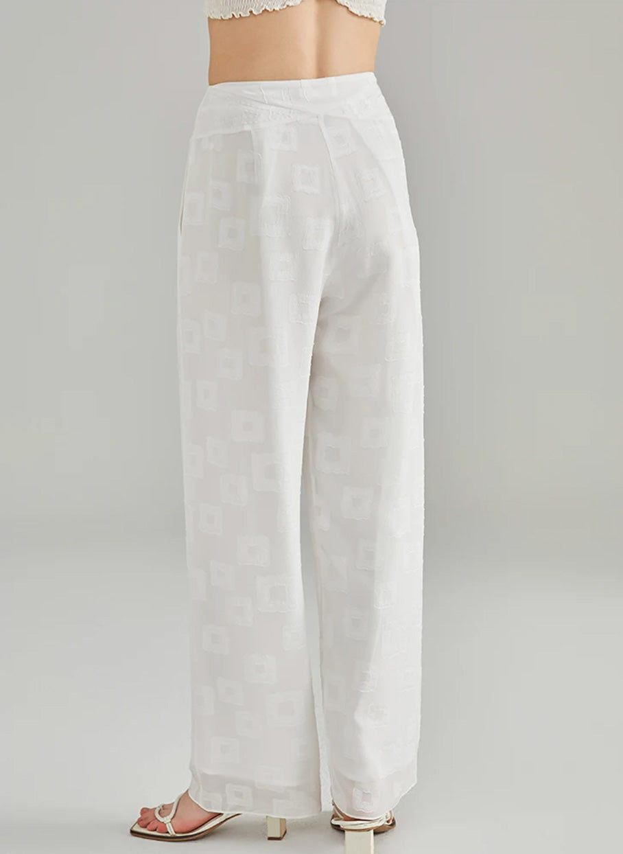 Rear view of a model showcasing the fit and angled pieced yoke of white Mulberry silk jacquard trousers — From Borcelleclothes.