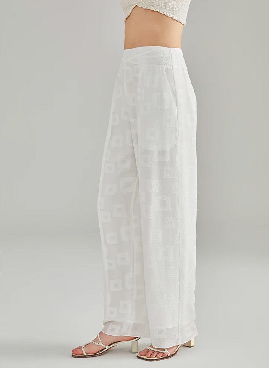 Left side profile of a model showing the straight-leg silhouette and concealed zipper of white silk trousers — From Borcelleclothes.