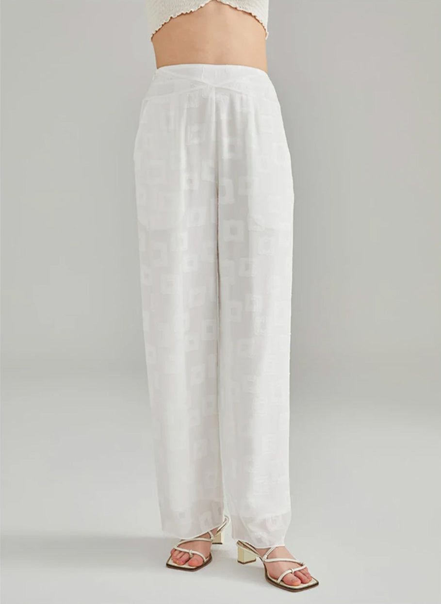 Front full-length view of a model posing with one leg aside wearing white straight-cut Mulberry silk jacquard trousers — From Borcelleclothes.