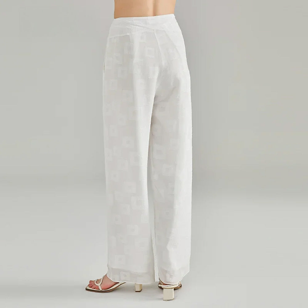 Back silhouette of a posing model wearing double-layered white silk palazzo trousers — From Borcelleclothes.