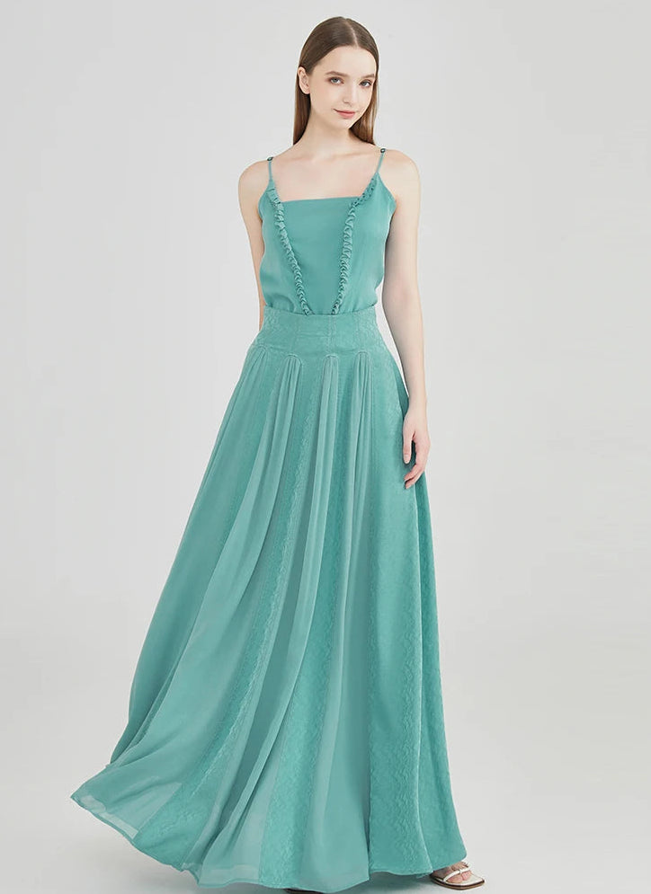A graceful shot of the model with her hand behind her back, emphasizing the fitted high waist and stately posture in the silk maxi skirt — From Borcelleclothes.