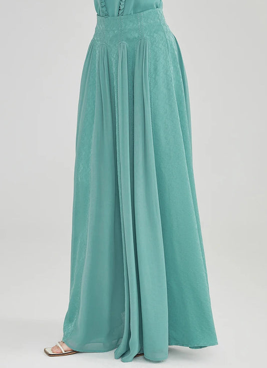 A model turned slightly to the side showcasing the flowing silhouette and elegant drape of the aqua-mint Mulberry silk maxi skirt — From Borcelleclothes.