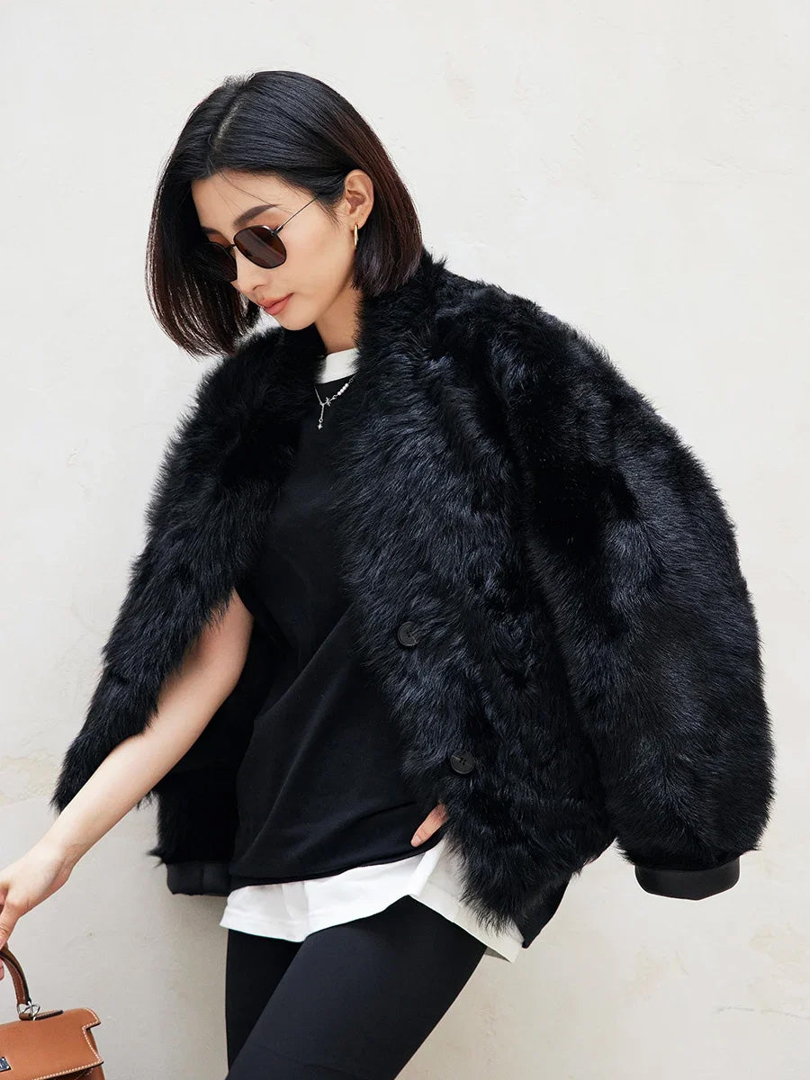 Model bending toward a bag in the Autographe cropped shearling jacket, fur side facing out — From Borcelleclothes.