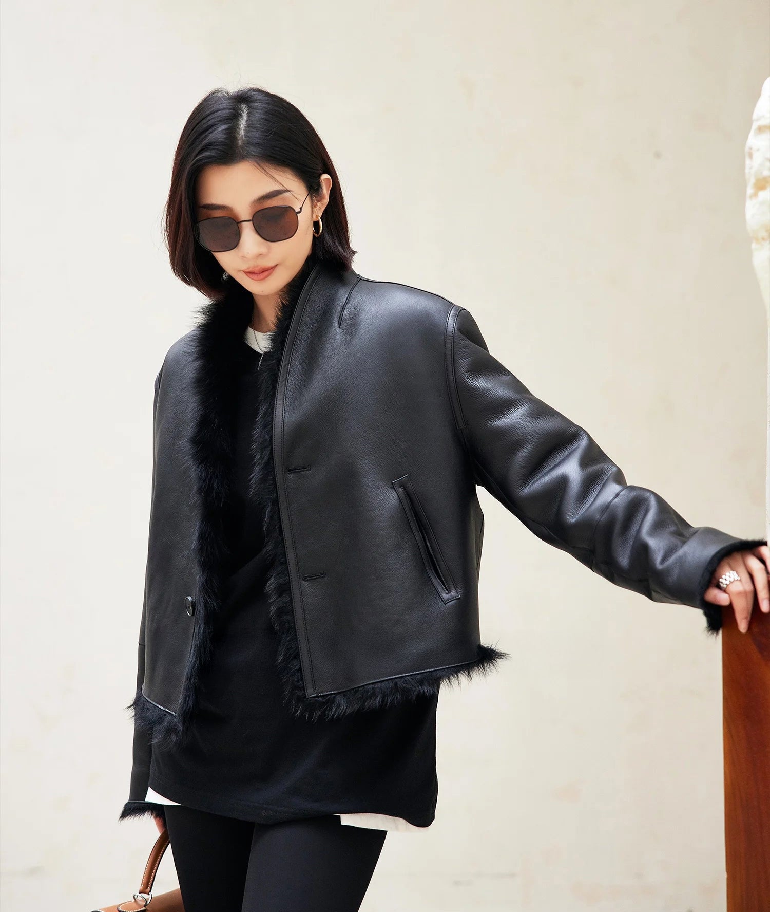 Model resting her hand on a wooden surface while wearing the Autographe reversible cropped shearling jacket, leather side out — From Borcelleclothes.
