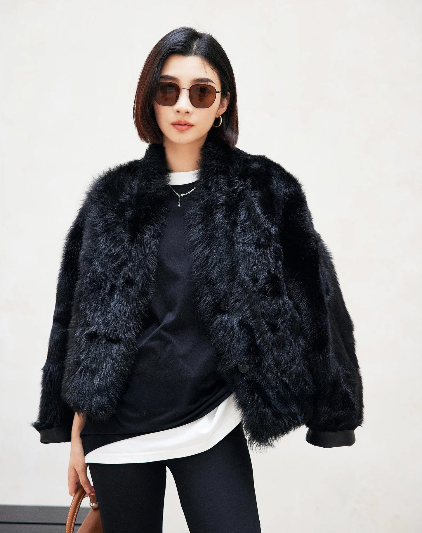 Model wearing the Autographe reversible shearling jacket draped over the shoulders, fur side visible — From Borcelleclothes.