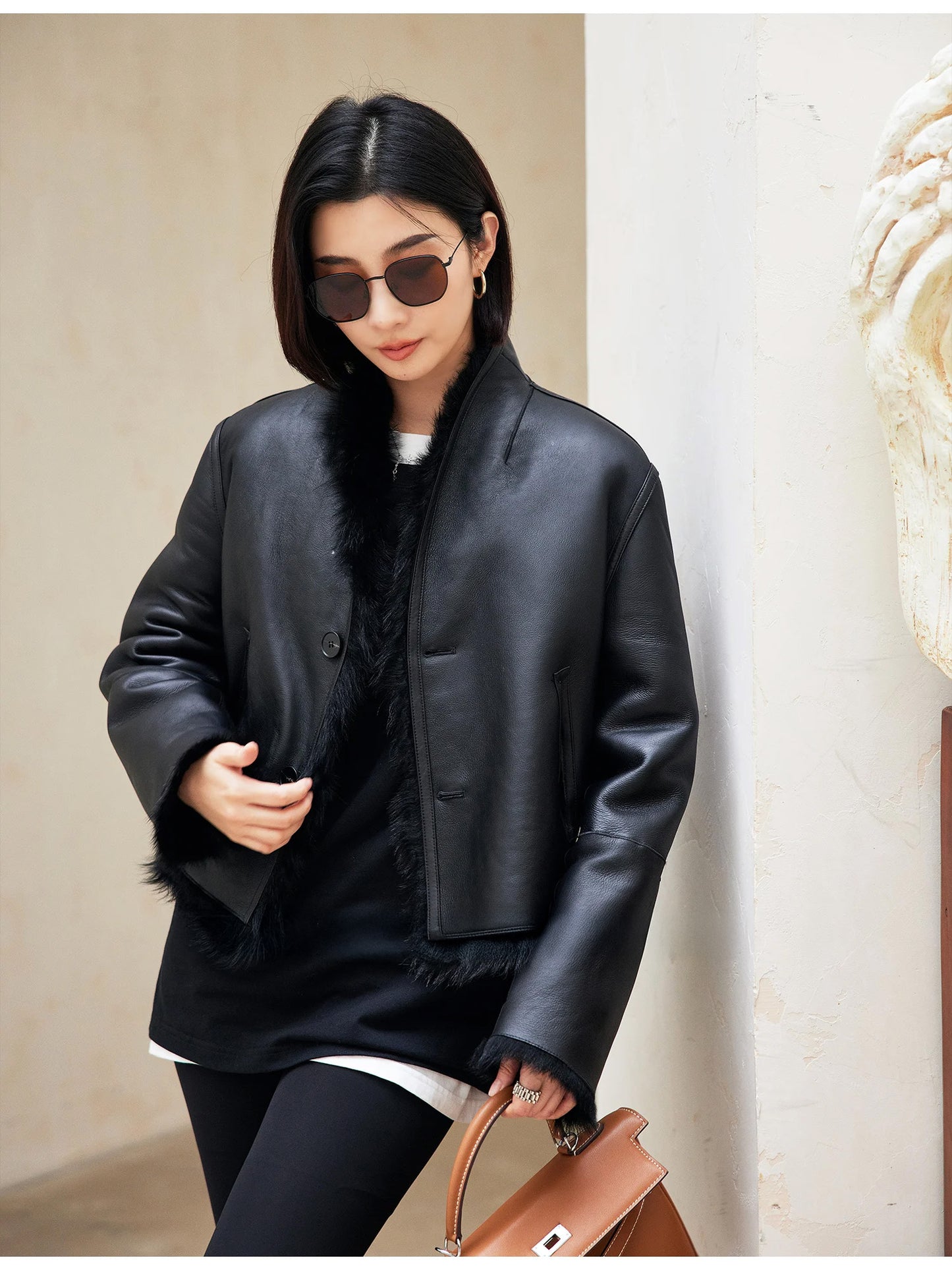 Model touching the front edge of the Autographe jacket, leather side visible — From Borcelleclothes.