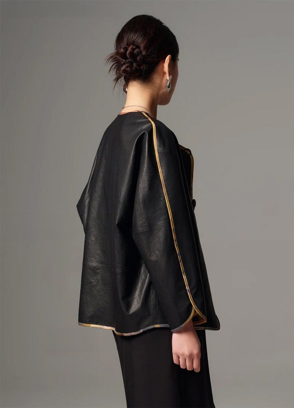 Side profile view highlighting the curved hemline and relaxed kimono silhouette in black Nappa — From Borcelleclothes.