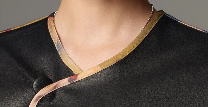 Close-up of the asymmetric crossover V-neckline framed with printed textile binding on black Nappa — From Borcelleclothes.
