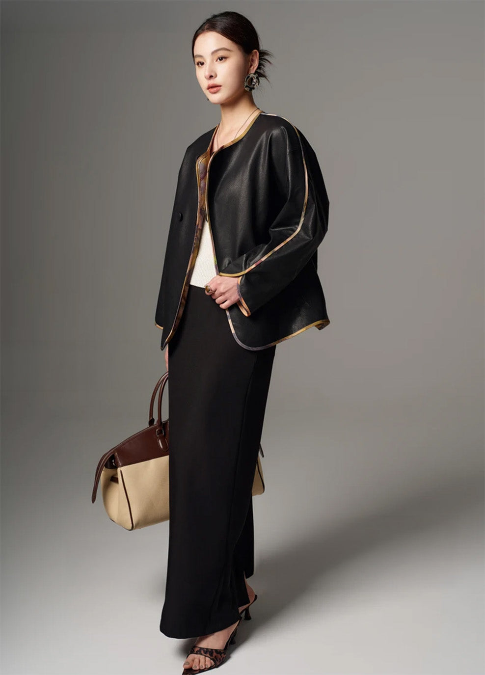 Model holding the front bound edge of the unfastened Nappa leather jacket — From Borcelleclothes.