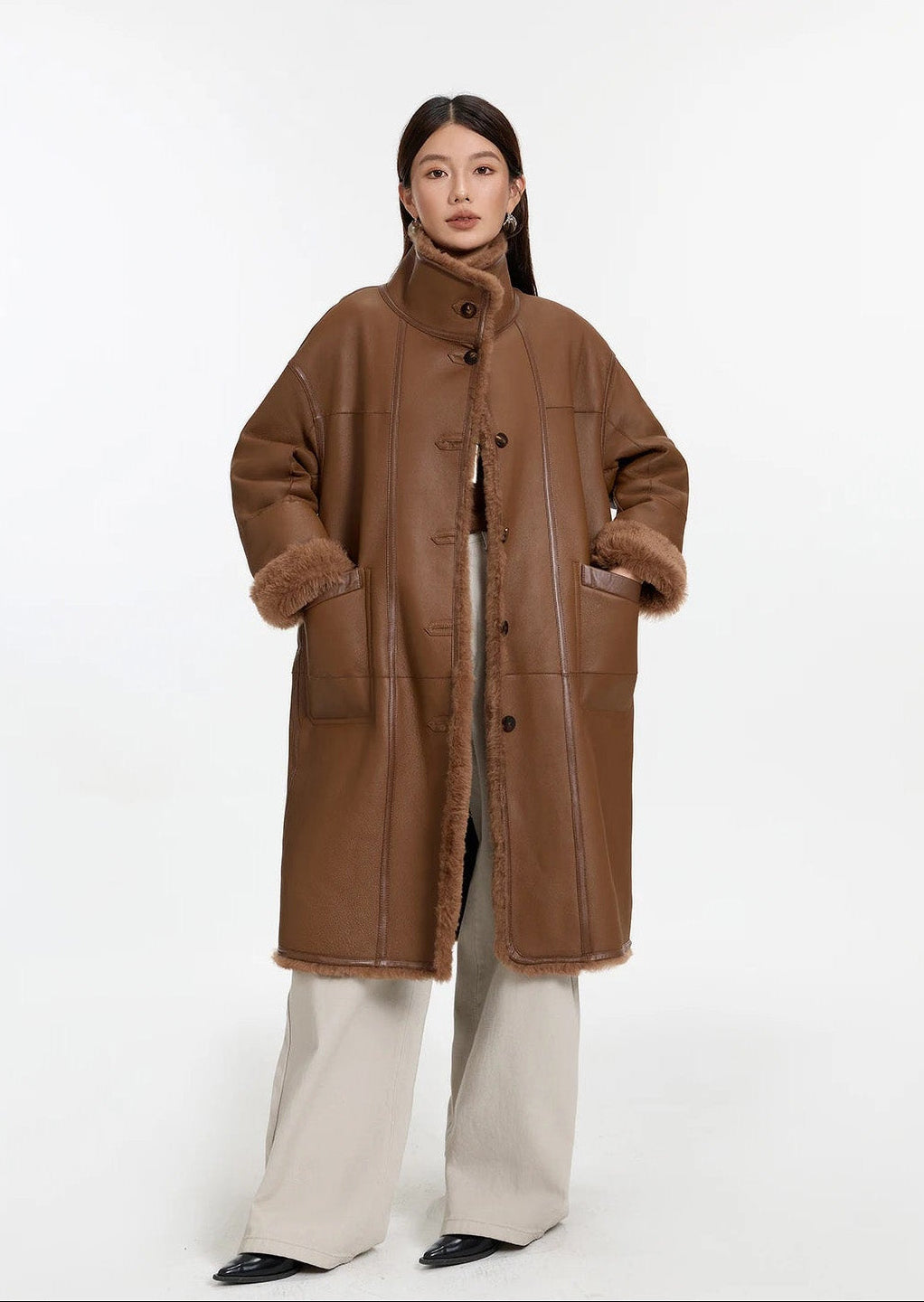 Model wearing the Cedar Resin reversible shearling coat, hands in pockets, leather side out — From Borcelleclothes.