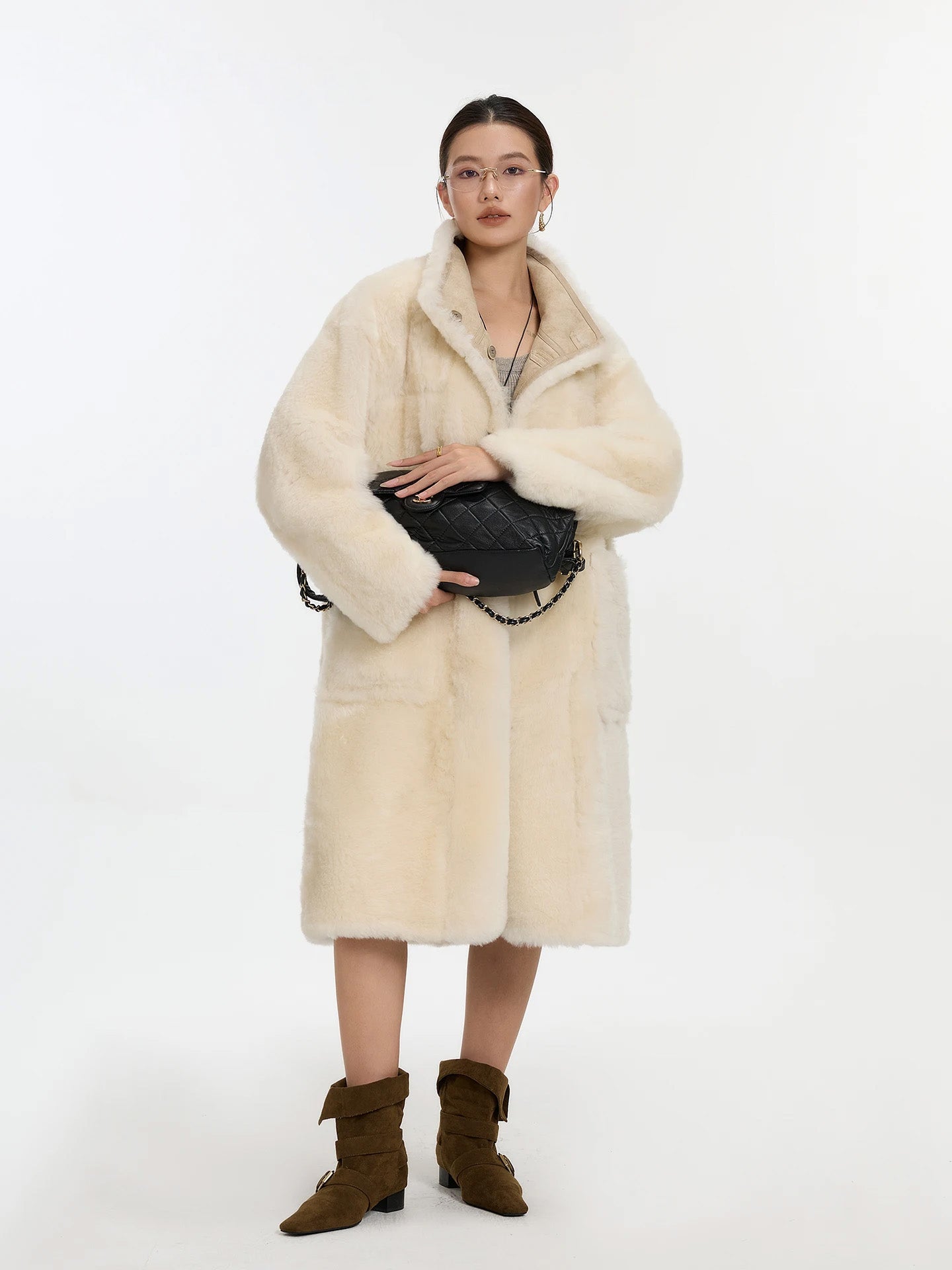 Model holding a bag with both hands, wearing Oatmeal Wax shearling coat, fur side out — From Borcelleclothes.