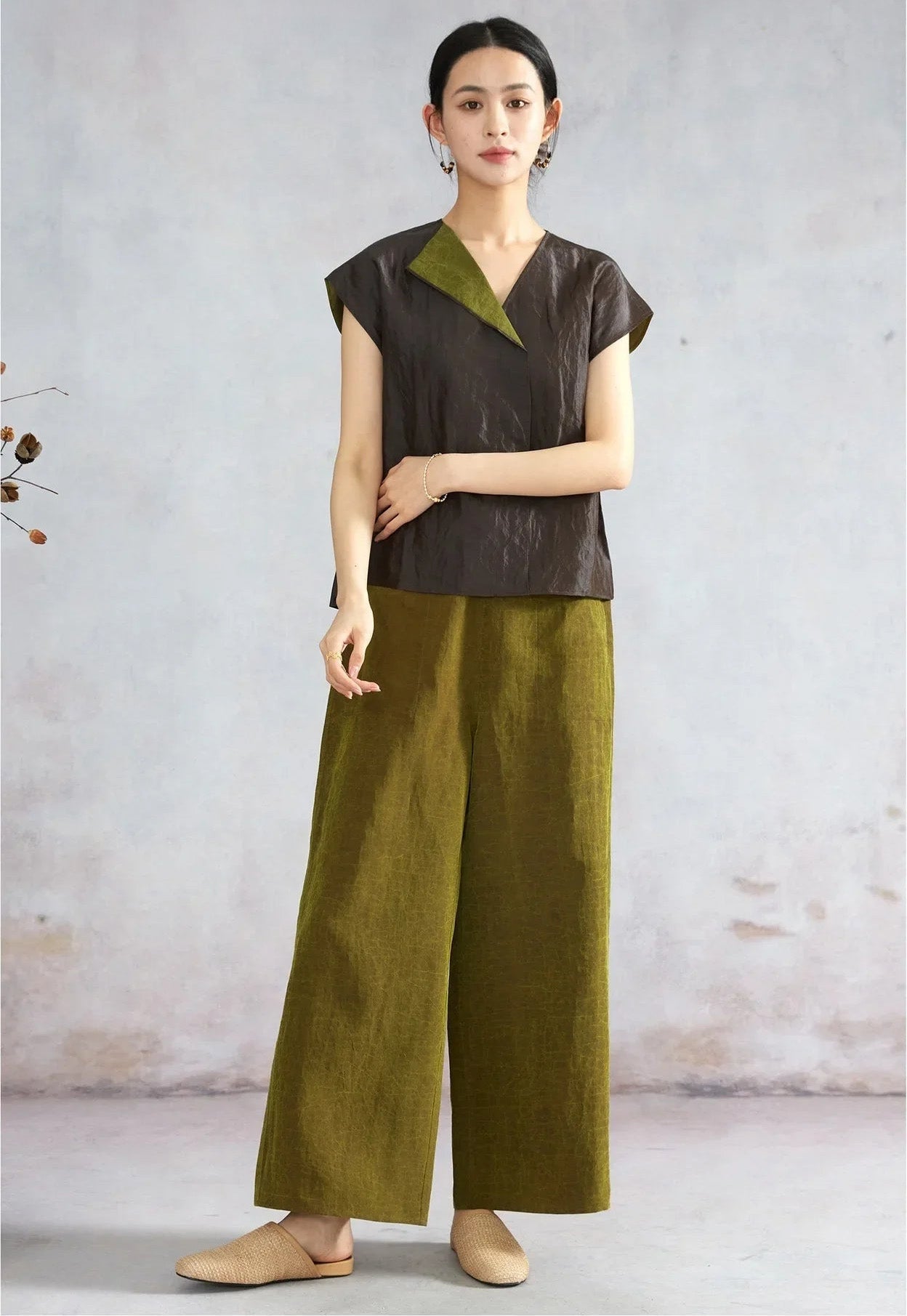 Woman with bent arm showcasing a black reversible silk top — From Borcelleclothes.