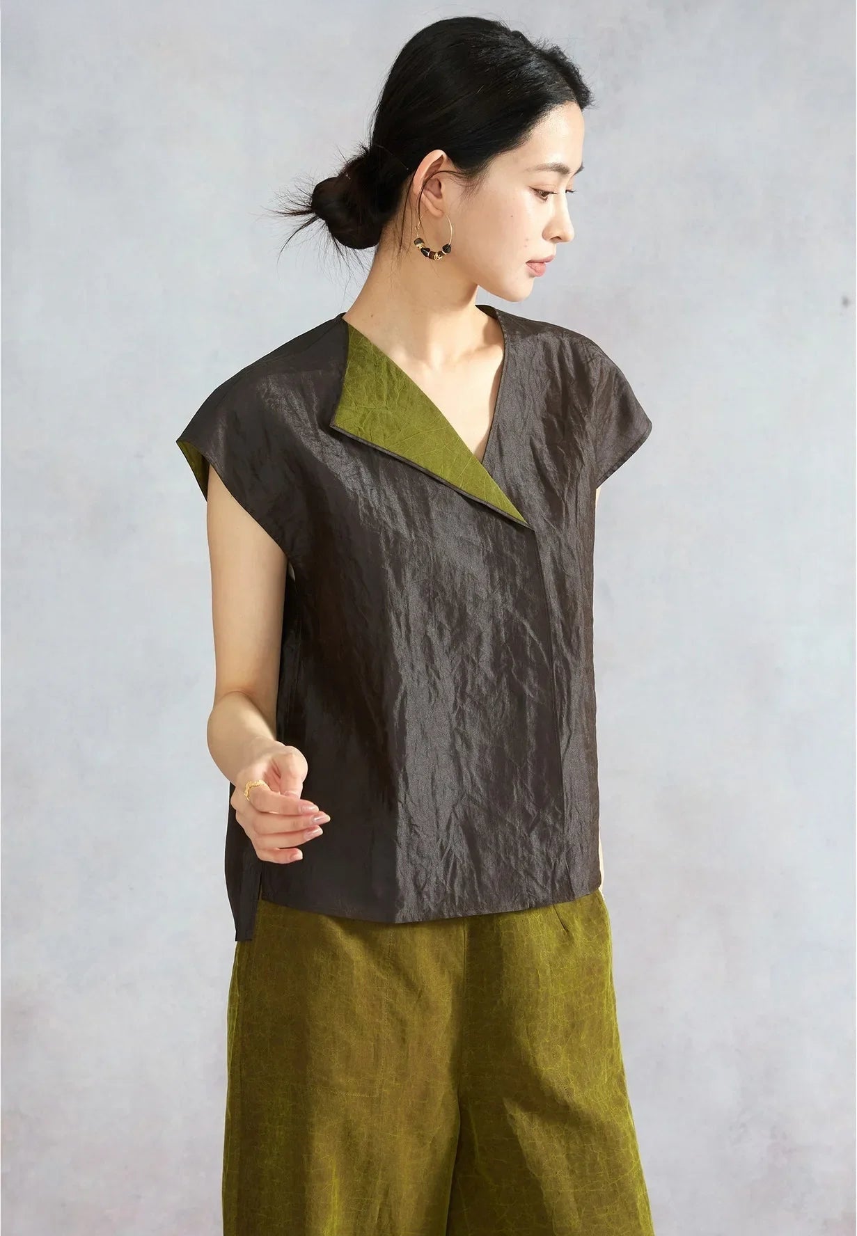Woman with bent arm looking down in a black reversible silk top — From Borcelleclothes.