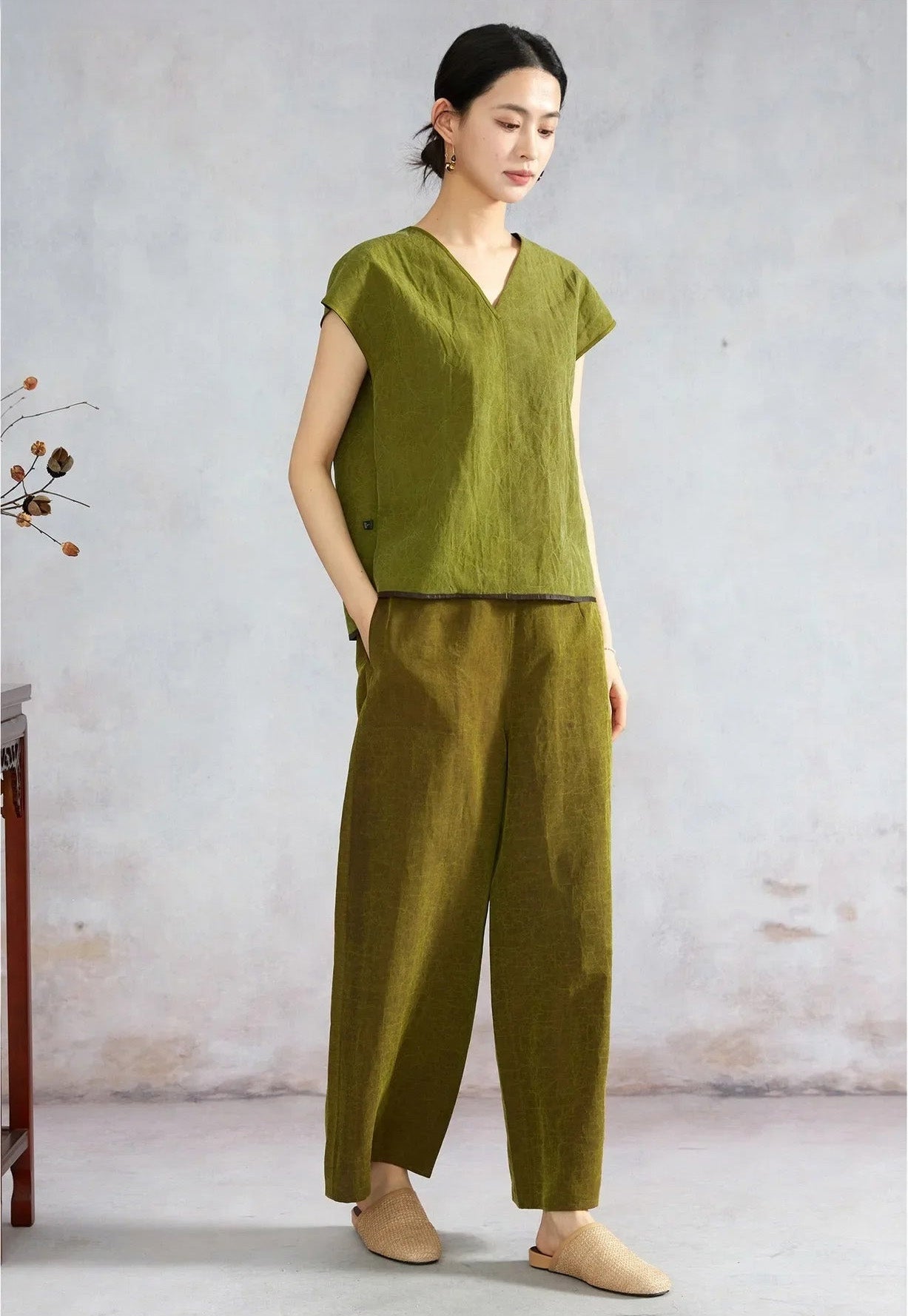 Woman turned slightly side showing an olive Xiangyunsha silk top — From Borcelleclothes.