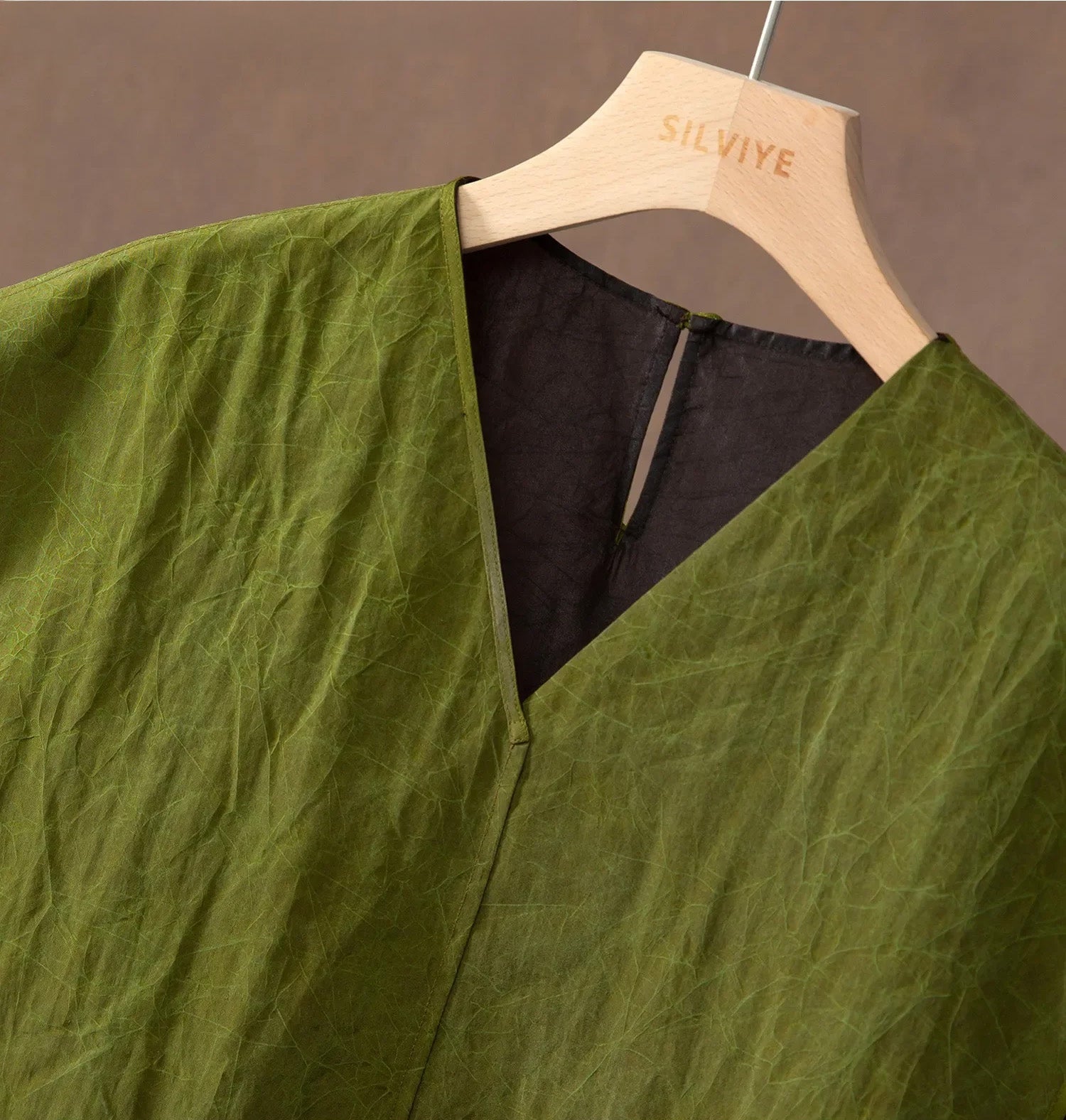 Detail of the V-neckline on an olive Xiangyunsha Mulberry silk top — From Borcelleclothes.