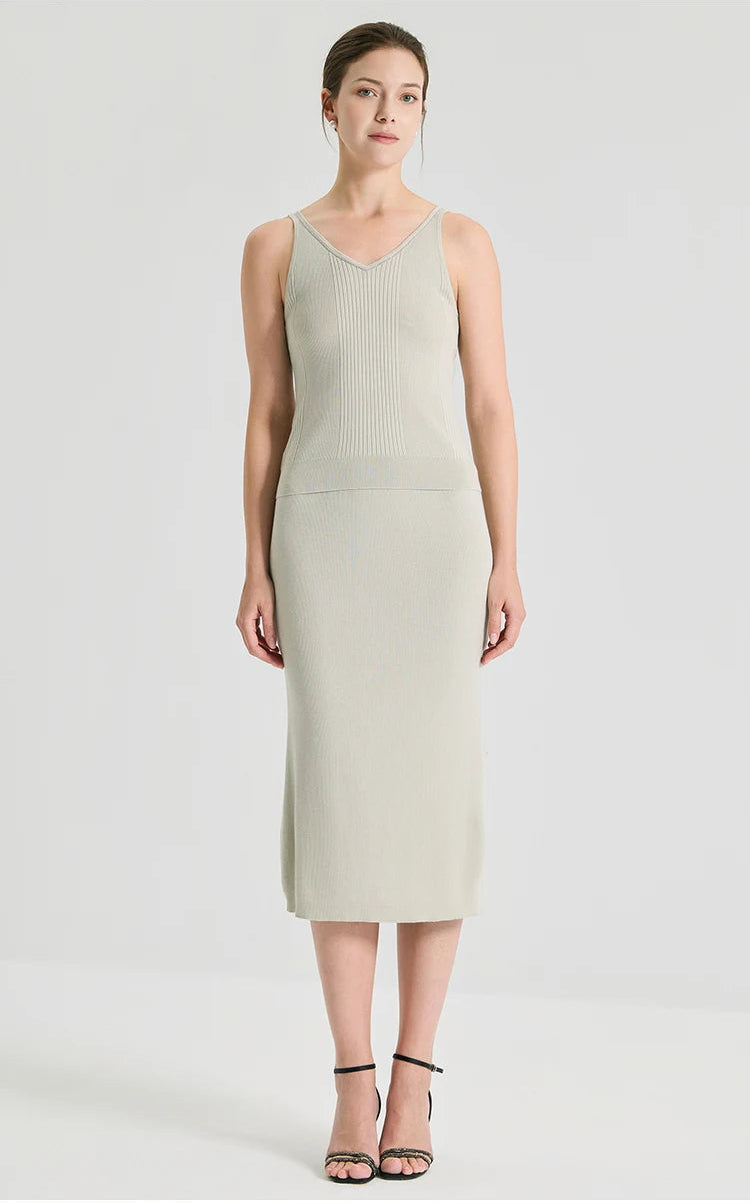 Full-height front view of a model standing straight in the sculptural mid-calf length wool-silk blend skirt in Compliant Sage green. From Borcelleclothes.