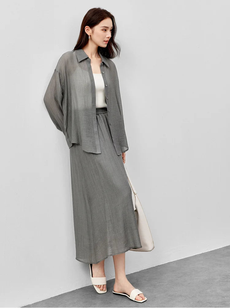 A woman leaning against a wall in a semi-sheer graphite rain lyocell two-piece set. — From Borcelleclothes.
