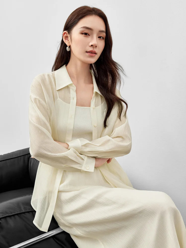 A woman seated with crossed arms wearing a semi-sheer pollen flight lyocell two-piece set. — From Borcelleclothes.