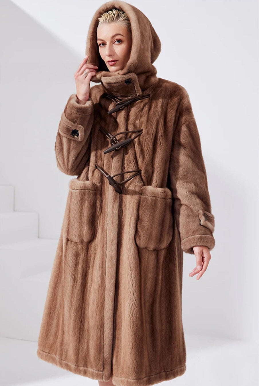 Model in a Dreamcatcher sheared mink coat, gently holding the edge of the lifted hood — From Borcelleclothes.
