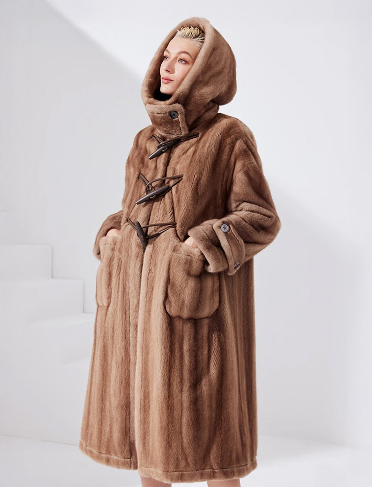 Model wearing a sheared mink coat in Dreamcatcher color with hood up, hands in side pockets — From Borcelleclothes.