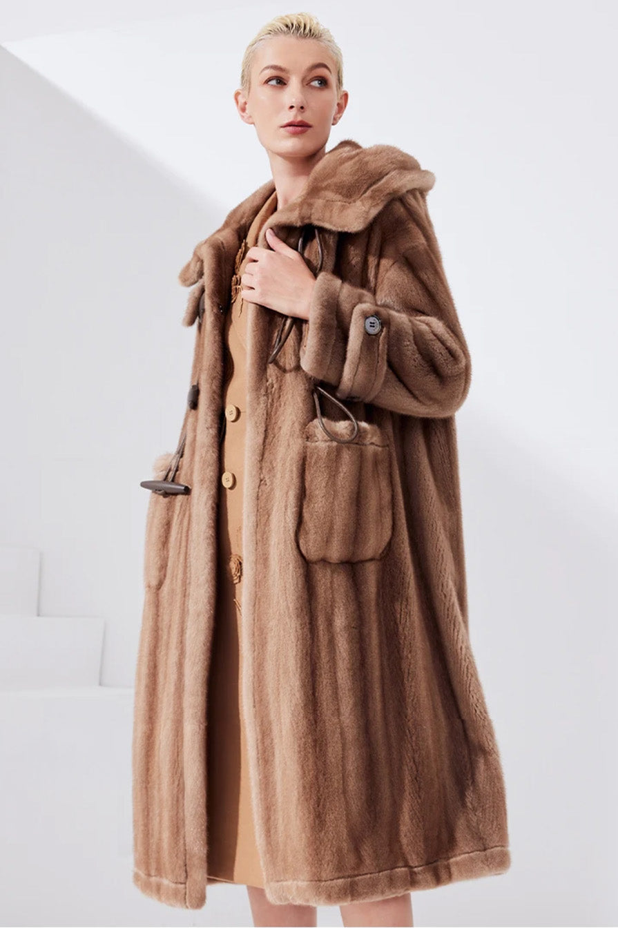 Model in sheared mink coat in Dreamcatcher color, touching the front edge of the coat near the closure — From Borcelleclothes.
