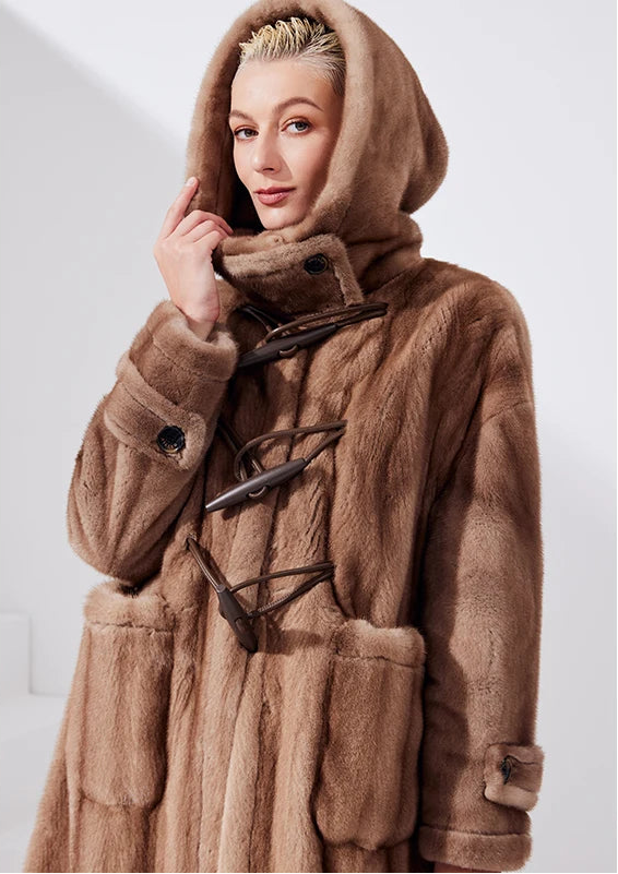 Upper part of a women's sheared mink coat in Dreamcatcher color, model wearing the hood, head slightly turned — From Borcelleclothes.