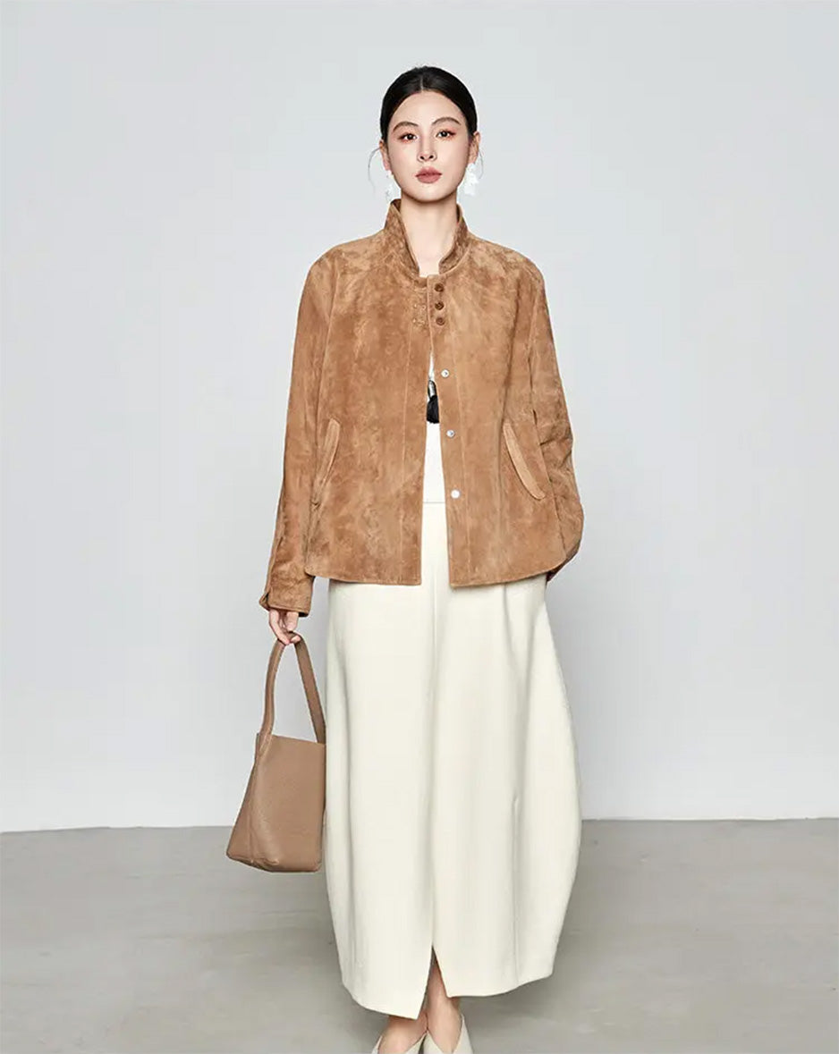 Full-length look of the Moiré Trace sheepskin suede jacket paired with a skirt, with the model holding an accessory bag — From Borcelleclothes.