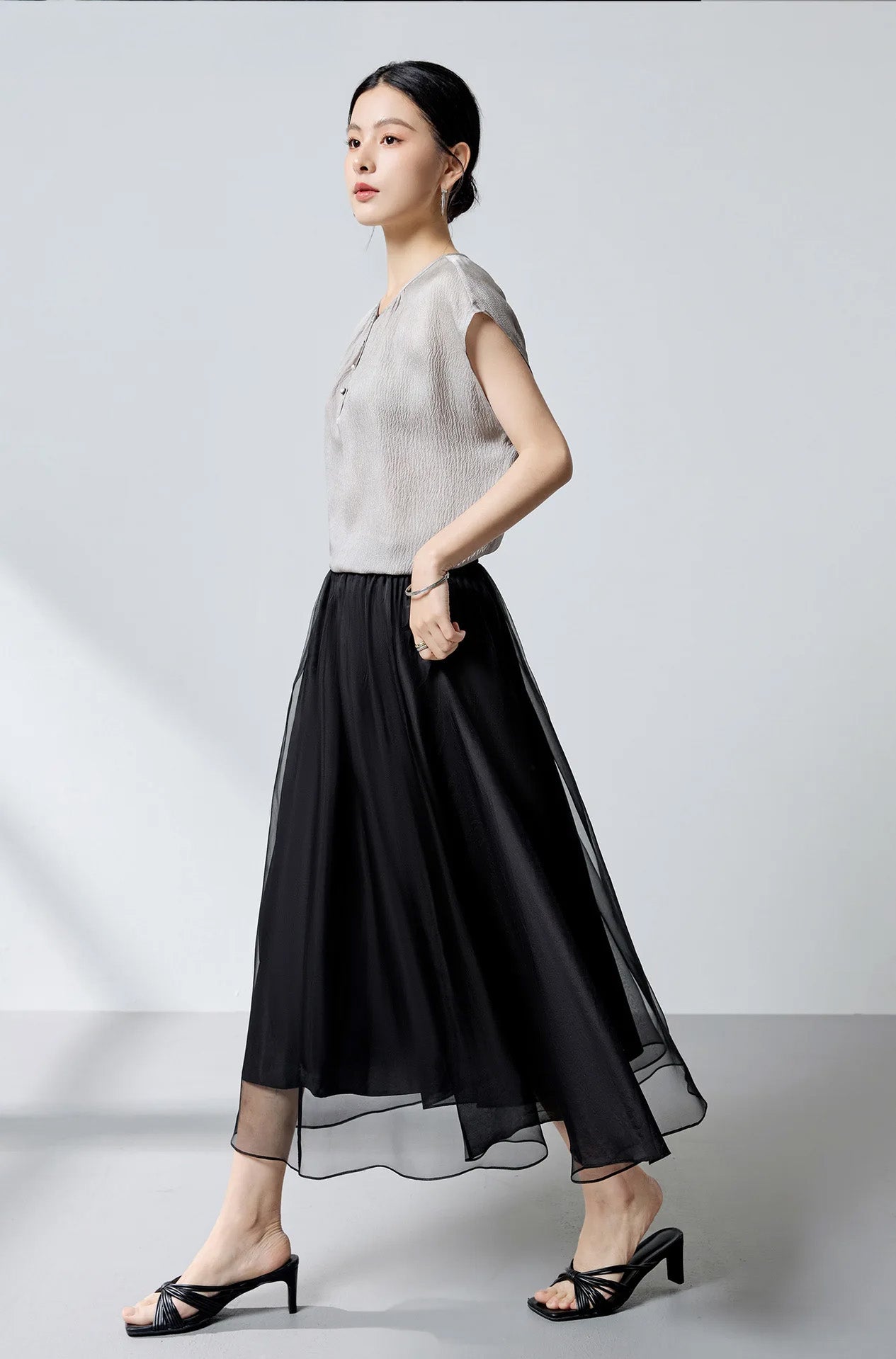 Side profile of model walking, demonstrating the fluid motion of the Where Lives Nacre silk blouse. — From Borcelleclothes.