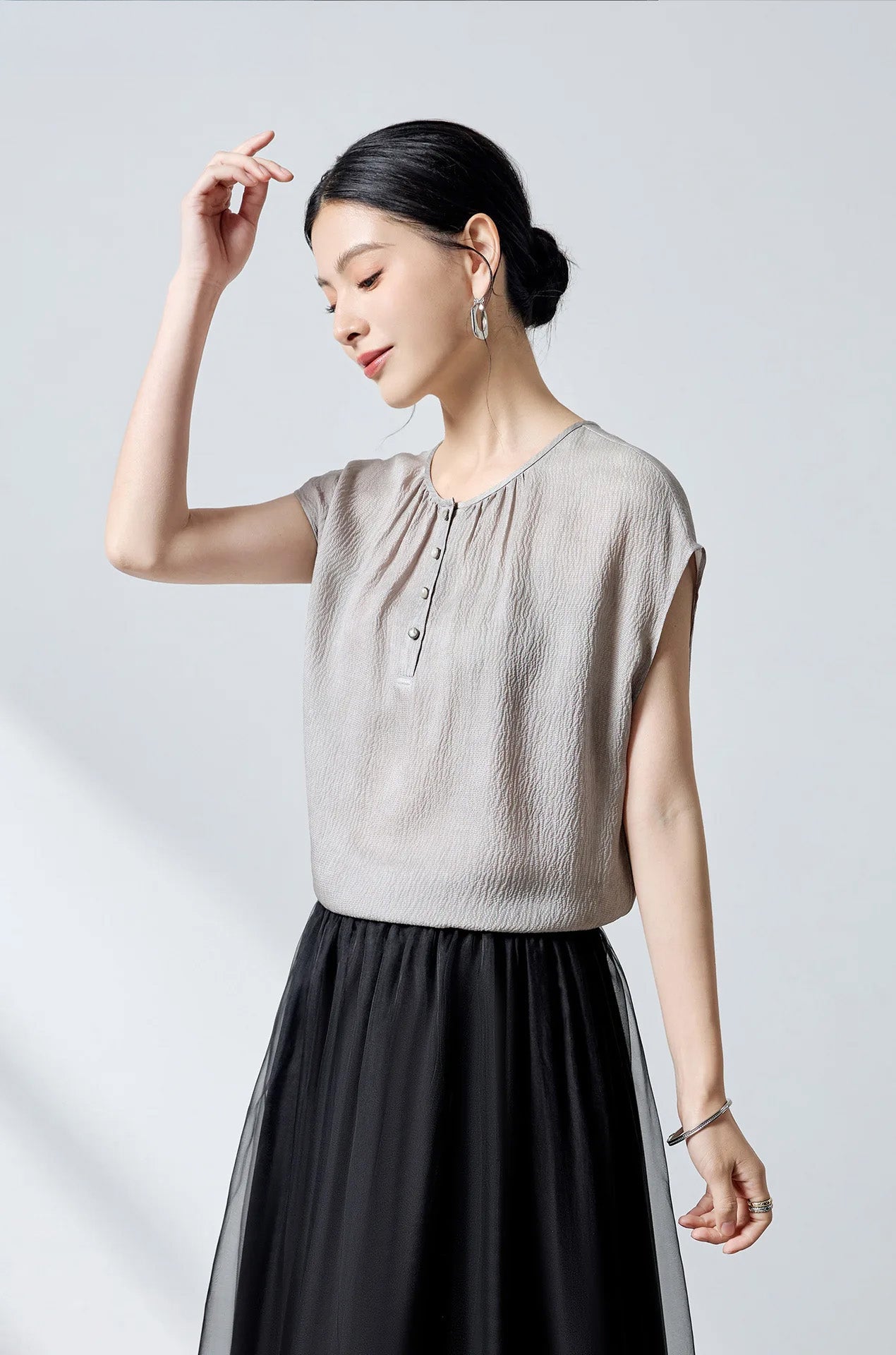 Model posing with hand near face, showing the round neckline and drape of the Where Lives Nacre silk blouse. — From Borcelleclothes.
