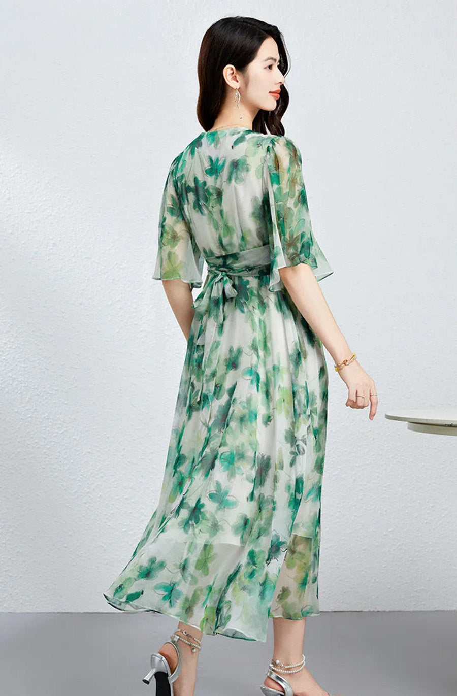 The back view of a woman in a Jade Breeze silk georgette dress, showing the integrated high waist seam and fluid midi length — From Borcelleclothes.