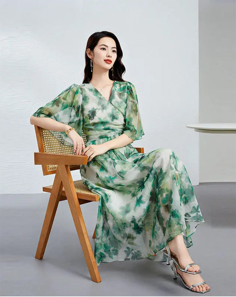 A woman seated gracefully in a Jade Breeze silk georgette flutter sleeve dress, showcasing the translucent drape of the fabric — From Borcelleclothes.