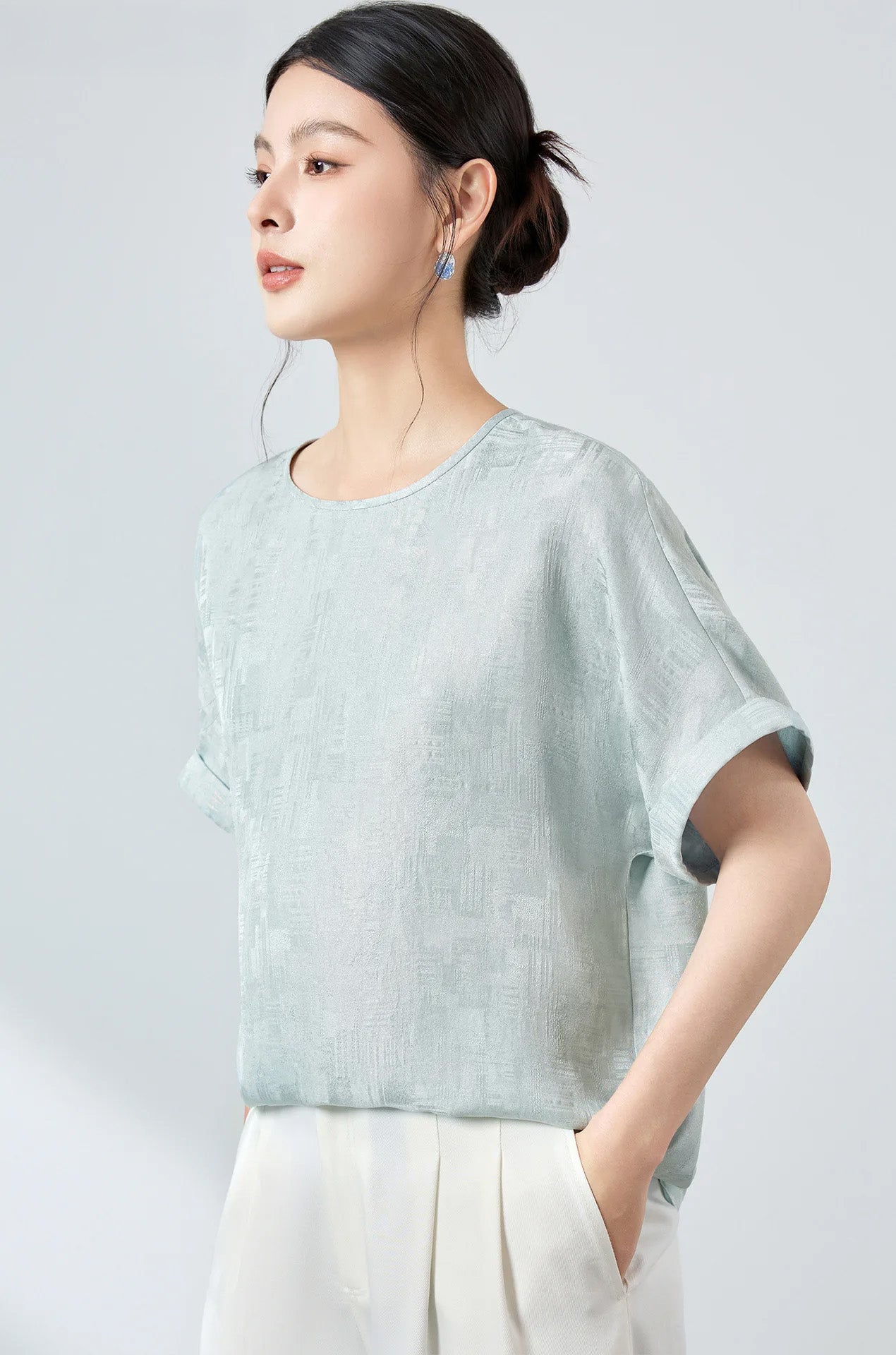 Three-quarter profile of model wearing a Glacial Spring Mulberry silk Sangbo jacquard top with soft light catching the woven texture — From Borcelleclothes.