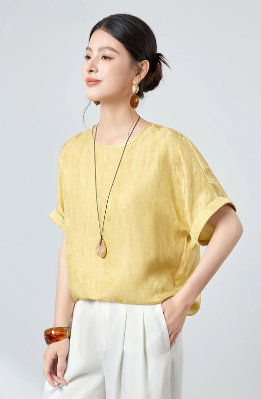 Model standing in a three-quarter profile wearing a women's Mulberry silk Sangbo jacquard blouse in Hakea with fluid drape — From Borcelleclothes.