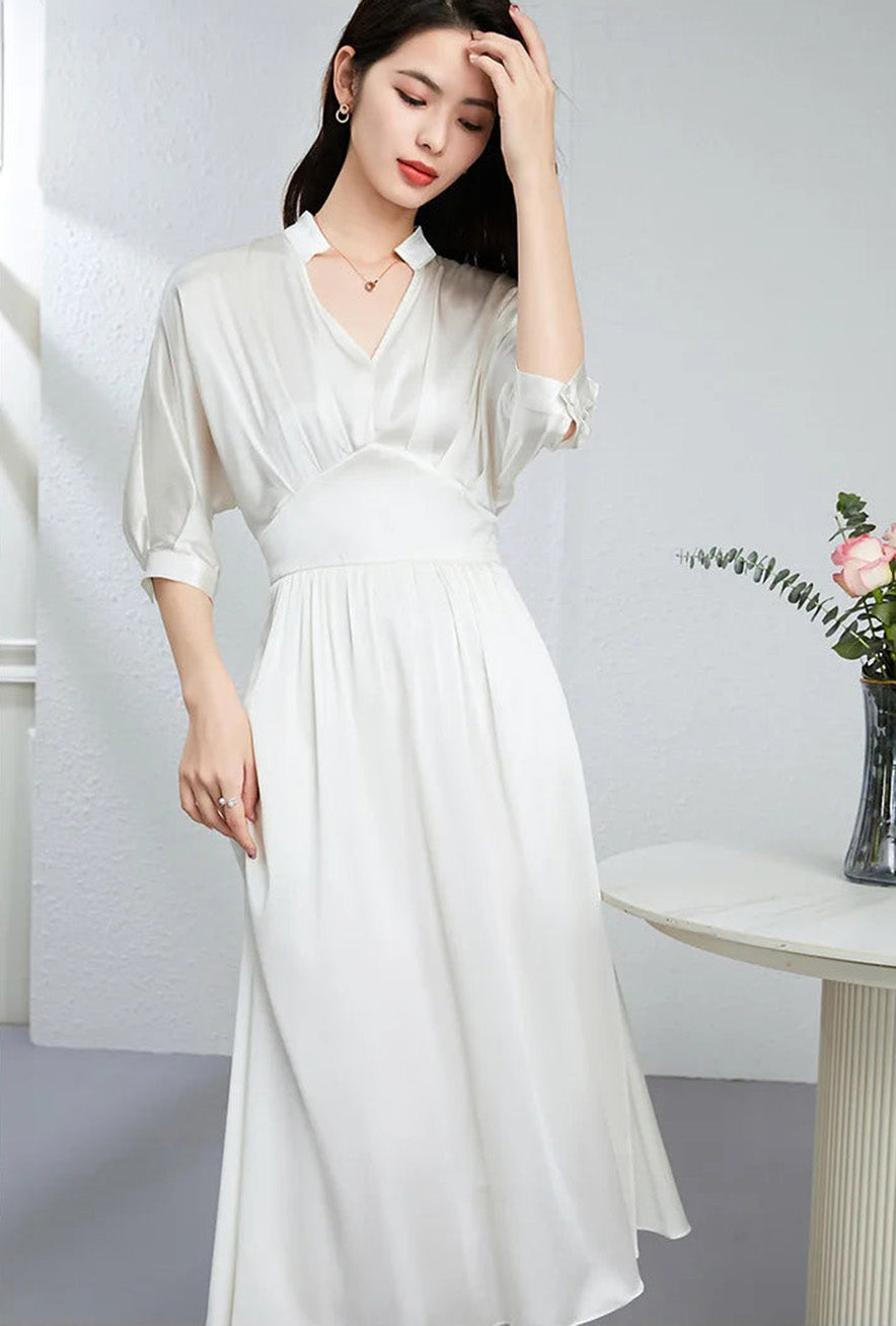 Woman in the Hot Ice white silk dress adjusting her hair, radiating effortless grace — From Borcelleclothes.