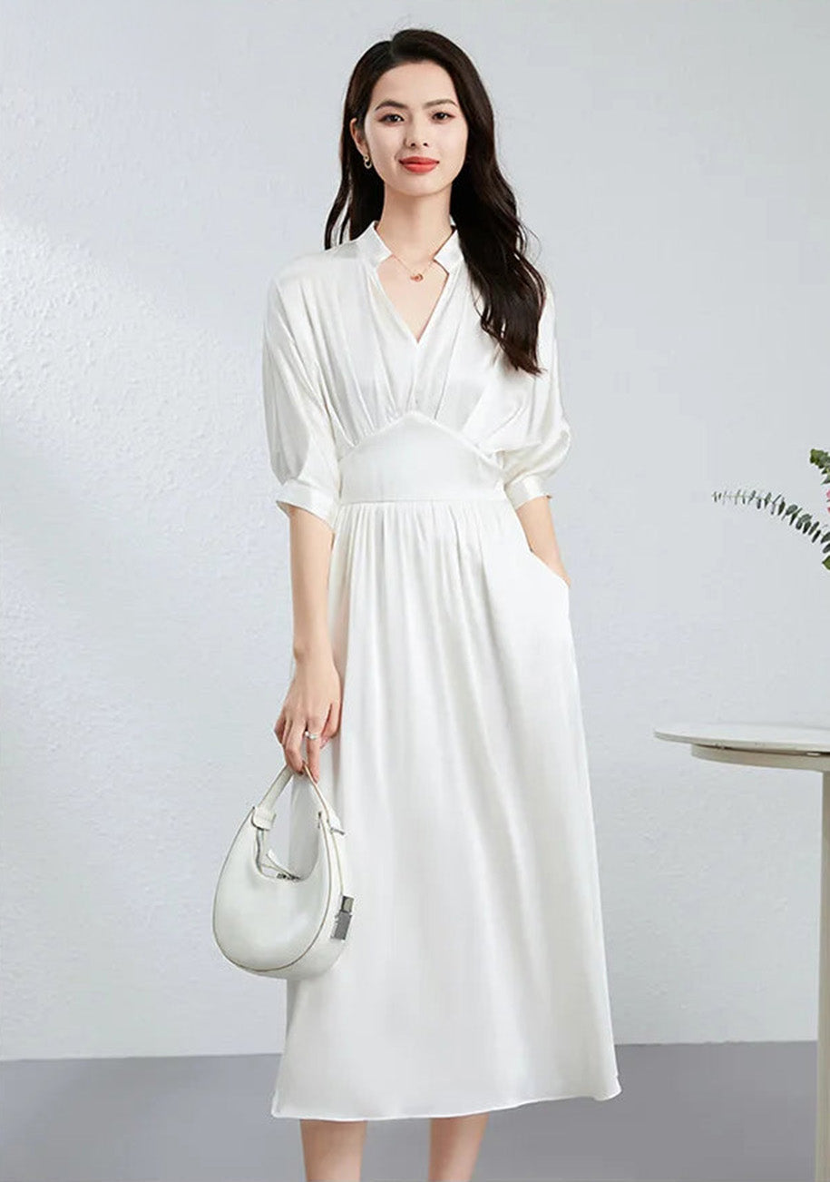 Sophisticated woman in Hot Ice white, pairing her silk dress with a white bag — From Borcelleclothes.