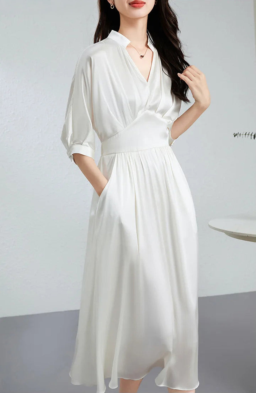 Serene woman in a Hot Ice dress with a hand in her pocket, touching her hair — From Borcelleclothes.