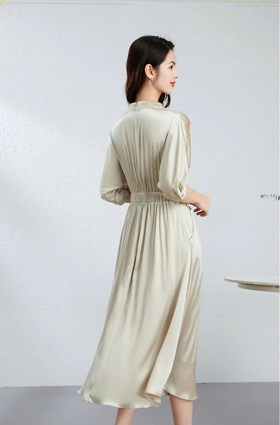 Rear view of a woman showcasing the graceful fall and back waist casing of the silk dress — From Borcelleclothes.