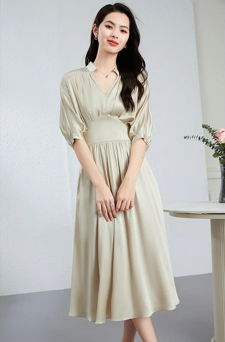 Sophisticated woman sitting with crossed legs, highlighting the fluid drape of the silk skirt — From Borcelleclothes.