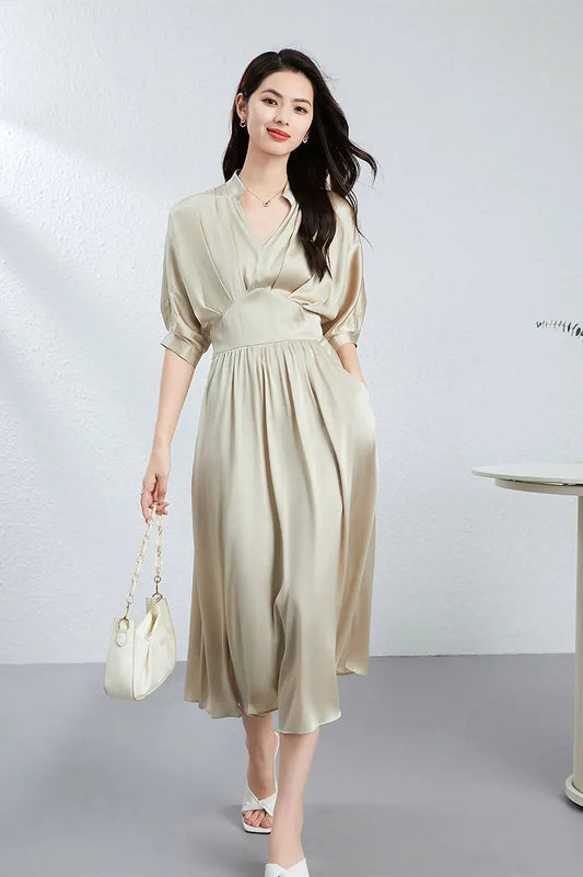 Elegant woman in a silk satin waist yoke dress in Taste of Champagne, holding a white bag — From Borcelleclothes.