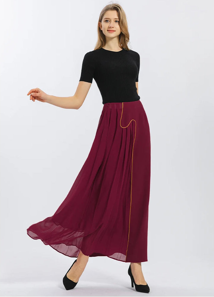 Flowing volume of the Carat Garnet silk maxi skirt during movement, capturing the dramatic play of light on pleated georgette and heavy crepe — From Borcelleclothes.