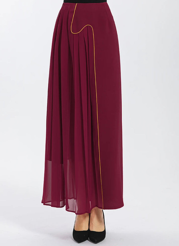 Asymmetric silk maxi skirt in Carat Garnet color, front view on model, structured with heavy 40 Momme crepe and fluid pleated georgette panels — From Borcelleclothes.