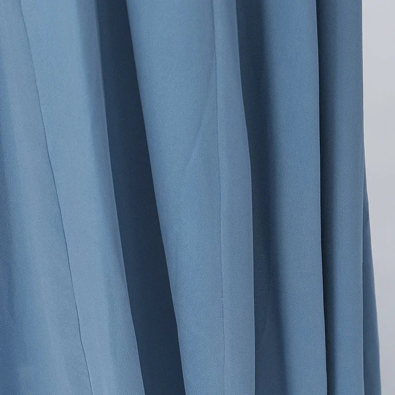 Macro shot highlighting the rich, fluid draping properties of the heavyweight 100% Mulberry silk, capturing the premium texture and deep, smoky-azure hue of the 'Wandering River' fabric. — From Borcelleclothes.