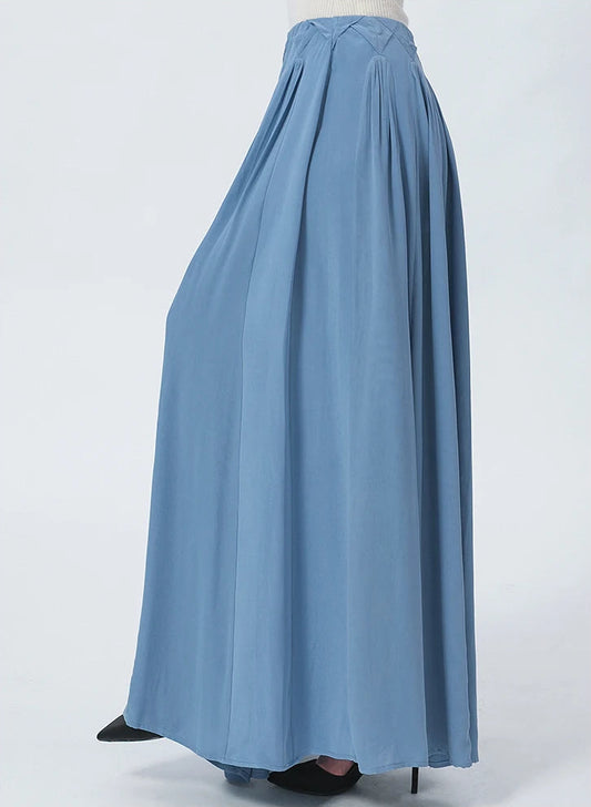 Side view of a model wearing the high-volume architectural maxi skirt in 'Wandering River' blue, showcasing how the heavyweight 6A Grade Mulberry Silk naturally drapes and contours the silhouette in movement. — From Borcelleclothes.