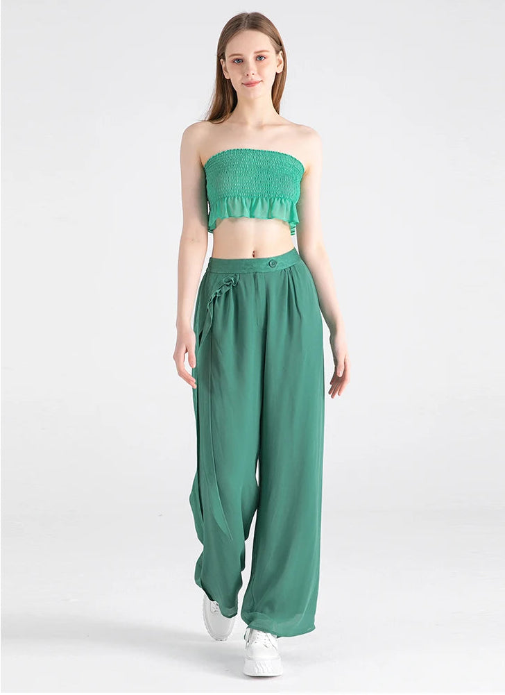 Model walking forward showing the fluid drape and motion of the double-layer silk georgette trousers — From Borcelleclothes.