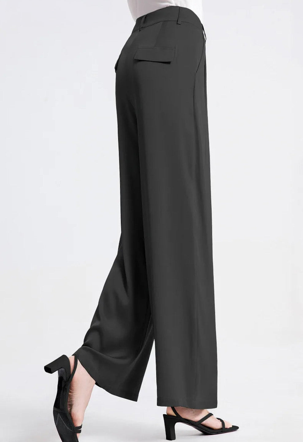 Side view of a model posing in Beyond Status dark Mulberry silk trousers. — Borcelleclothes.