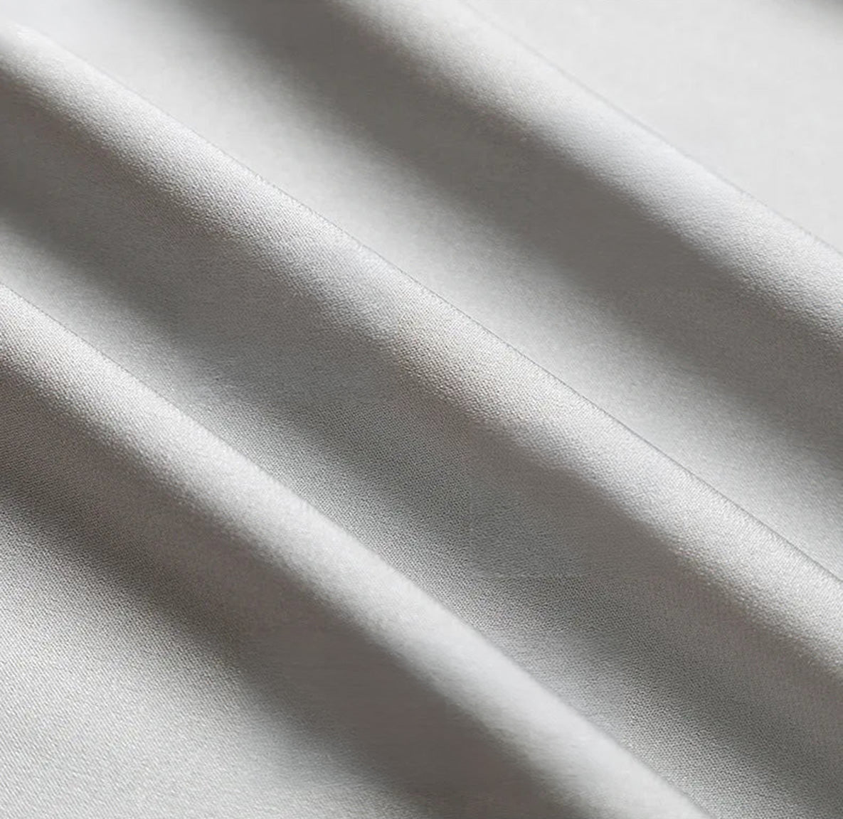 Detailed view of the wave-folded silk texture on gray wide-leg trousers. — Borcelleclothes.