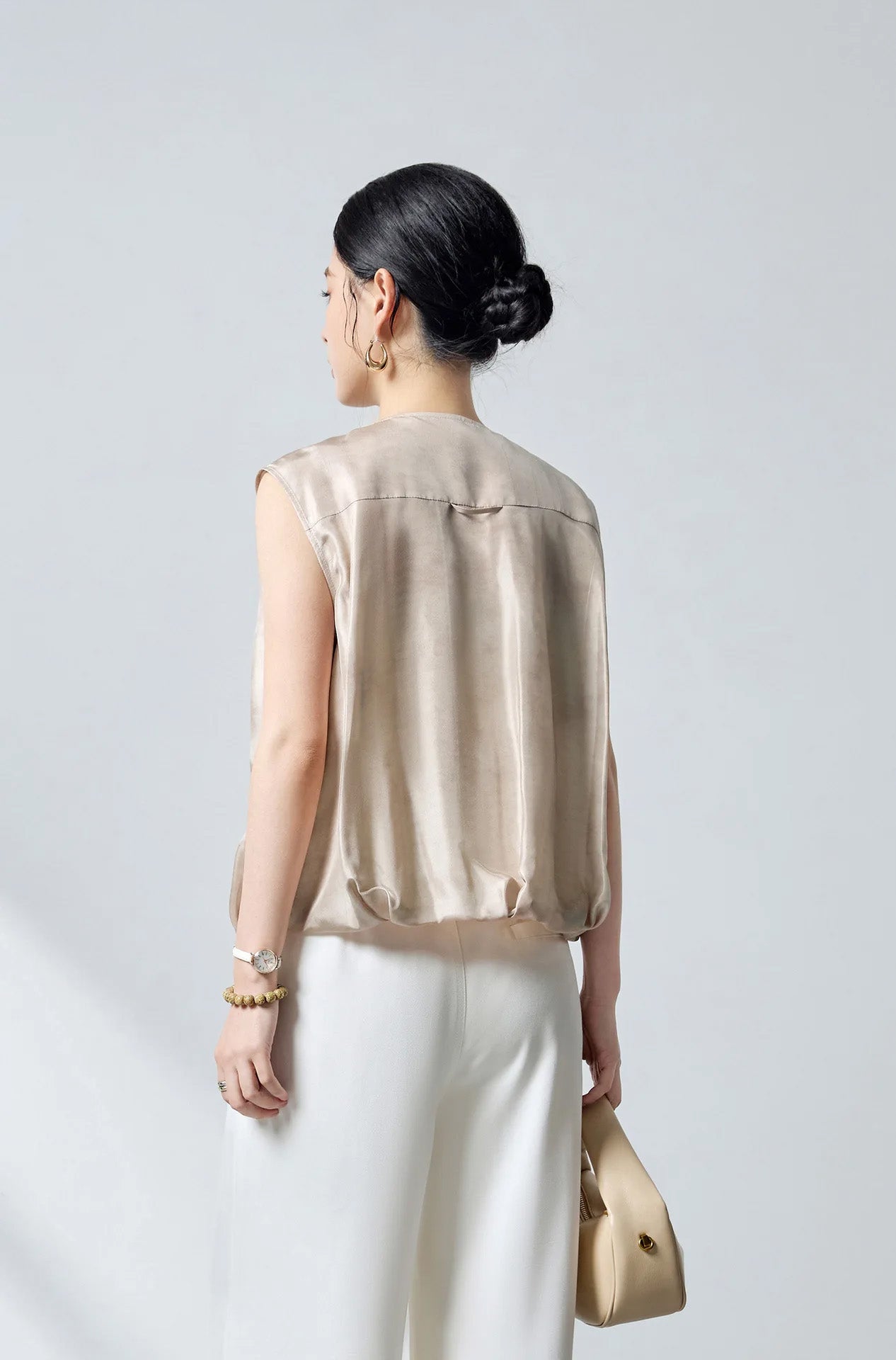 Back view of the model wearing the relaxed sleeveless Mulberry silk blouson jacket in Whispering Wind — From Borcelleclothes.